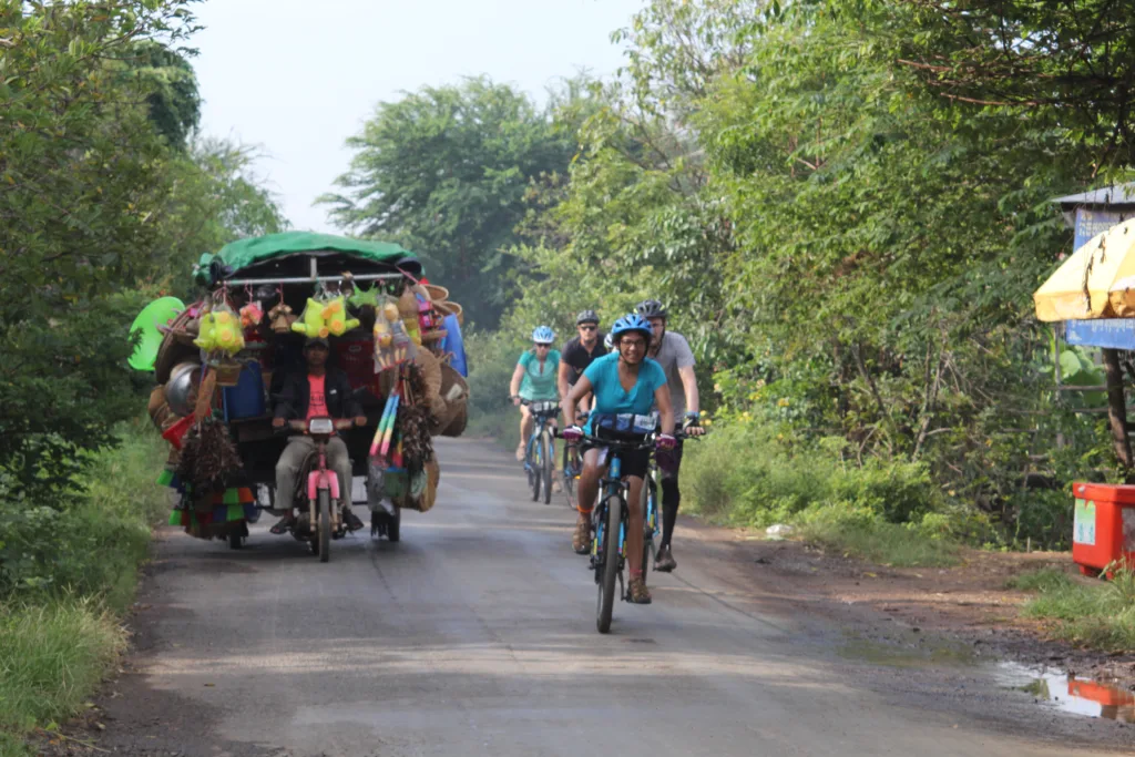 group-of-happy-cyclists-passing-local-cargo-bike-in-vietnam-on-bike-trip-from-vietnam-to-cambodia-with-360-expeditions